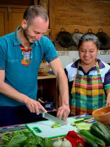 Guest learning to cook a vegetarian dish in the MayAchik kitchen